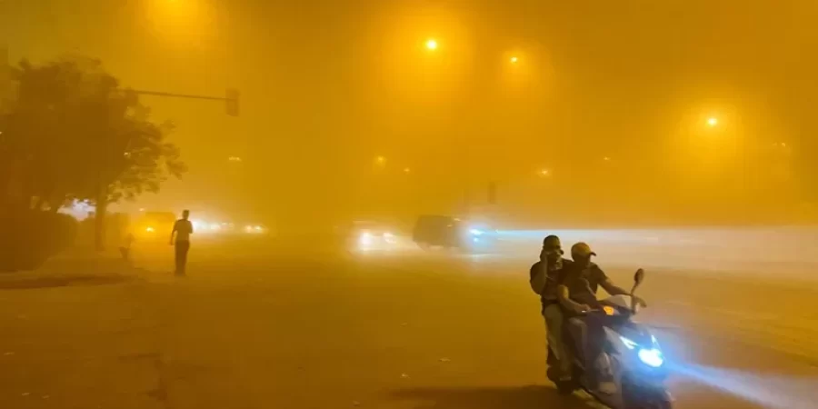 شخصان على دراجة نارية يجوبان شوارع العاصمة العراقية بغداد، خلال عاصفة رملية.
