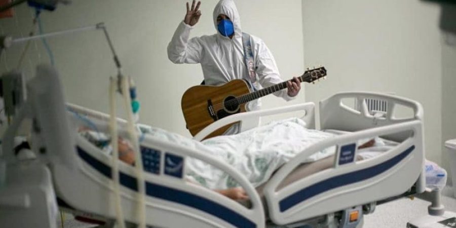 الموظف  يغني ويصلي من أجل مريض مصاب بـ كوفيد -19 داخل أجنحة المستشفى ومناطق العناية المركزة كجزء من احتفالات عيد الفصح، في 4 أبريل 2021.