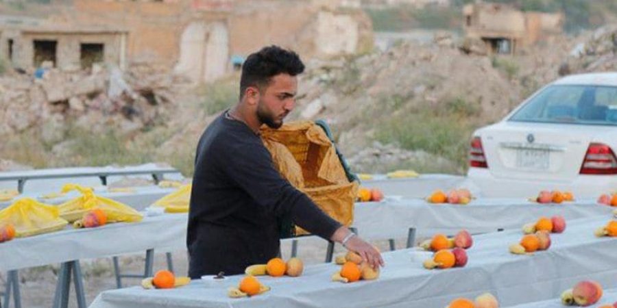 شاب يعد الطعام لوجبات الإفطار ويضع الفواكه على طاولة إفطار رمضان في الموصل