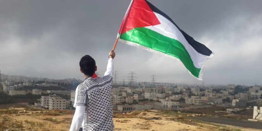 فلسطيني يرفع علم بلاده