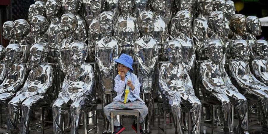 صبي يجلس على كرسي بين منحوتات معروضة في مركز تسوق في يوم الطفل العالمي