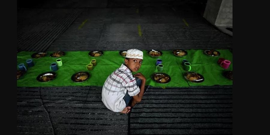مصل مسلم يجلس بجوار أطباق الطعام في مسجد نوي آي في اليوم الأول من شهر رمضان المبارك في يانغون