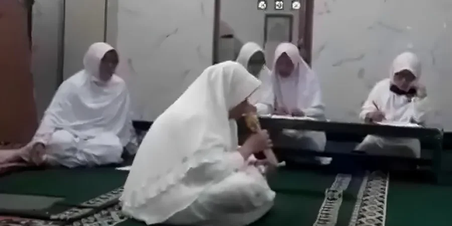 صورة التقطت من مقطع الفيديو الذي وثّق الوفاة تظهر فيه السيدة الراحلة وهي تجلس في الوسط أثناء قراءتها القرآن (صفحة نبراس-إندونيسيا على توتير)